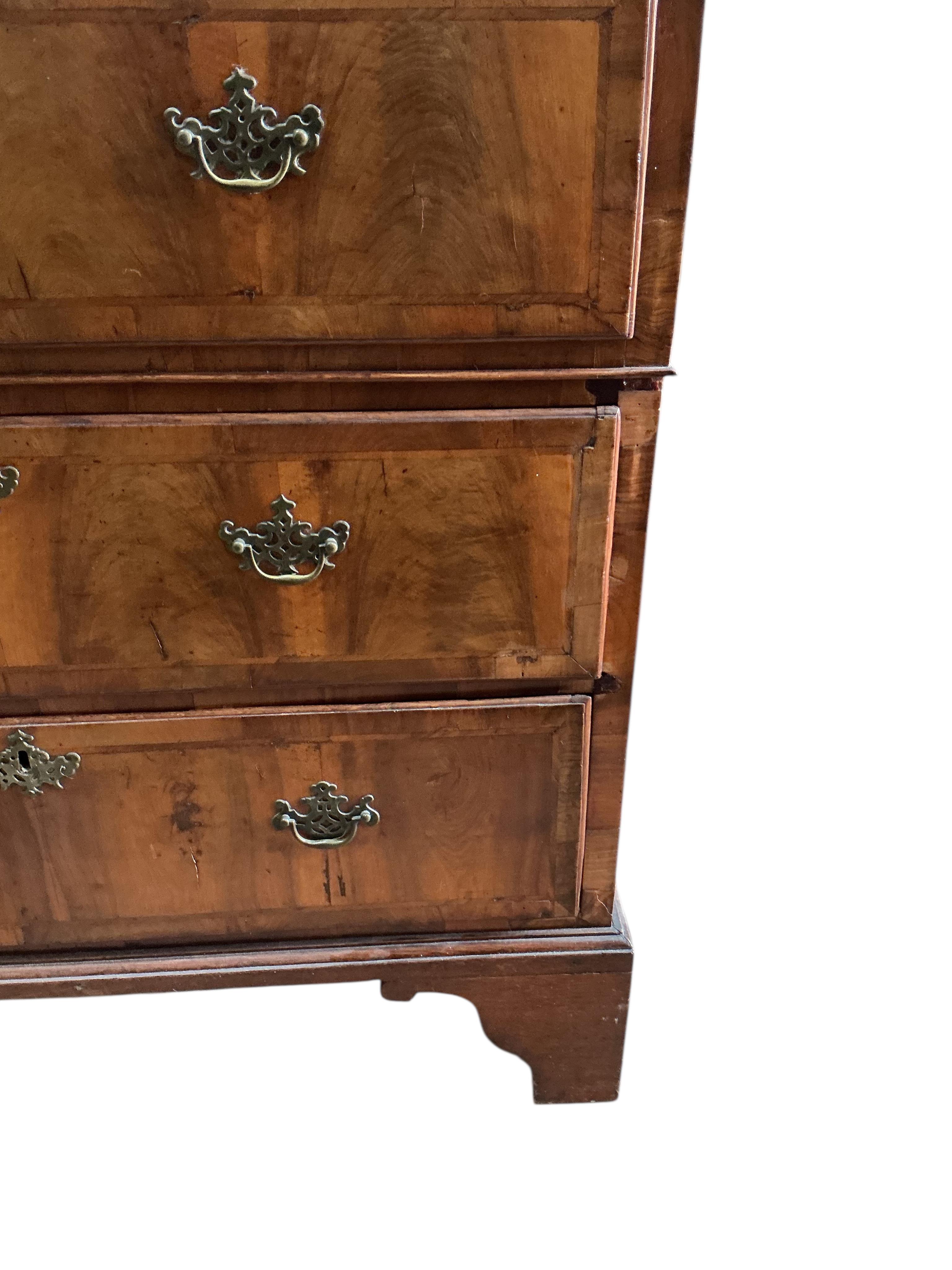 An early 18th century feather banded walnut and pine two section chest of drawers, on later bracket feet and with losses, width 96cm, depth 52cm, height 135cm